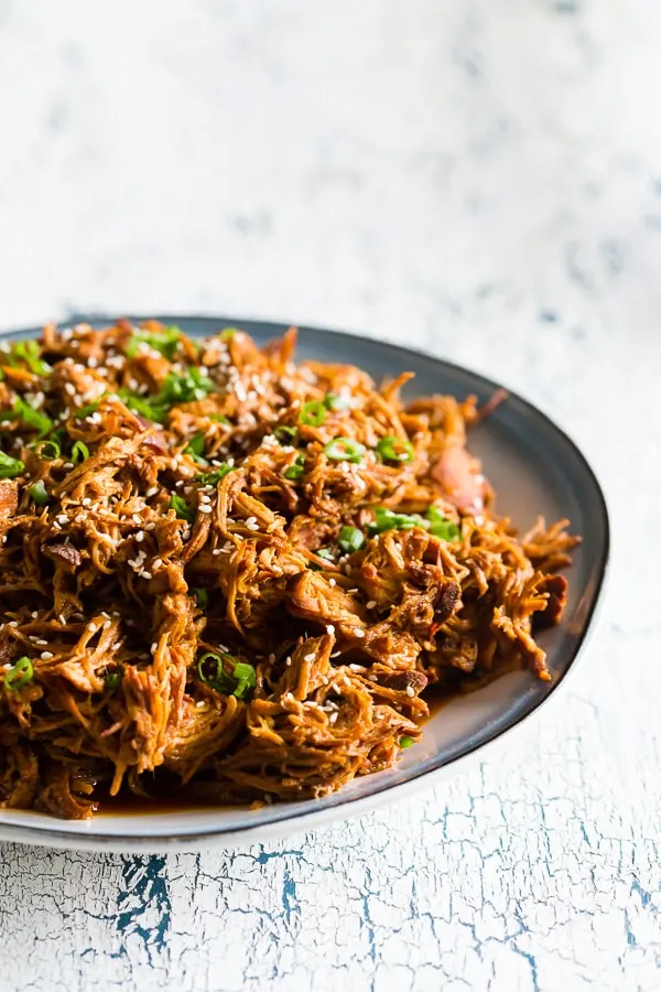 Slow Cooker Honey Sriracha Pulled Chicken on a plate with sesame seeds. 