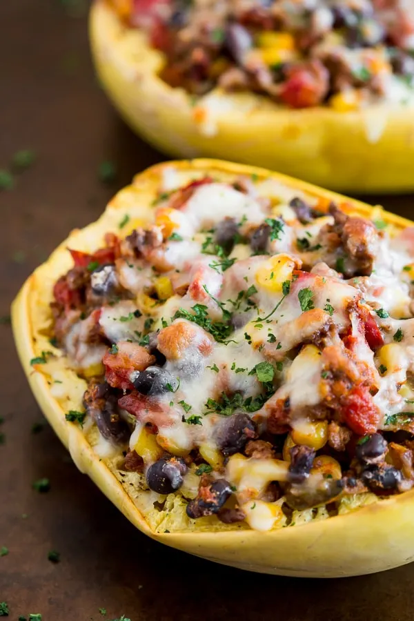southwest taco stuffed spaghetti squash on a sheet pan topped with cheese and herbs