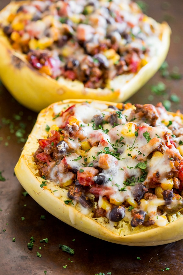 southwest taco stuffed spaghetti squash on a sheet pan topped with cheese