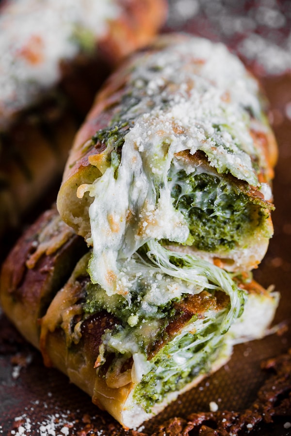 This cheesy pesto garlic bread is packed full of fresh garlic basil pesto and stringy mozzarella cheese. Super simple to make and full of flavor! You'll love how easy this bread side dish is to make! 