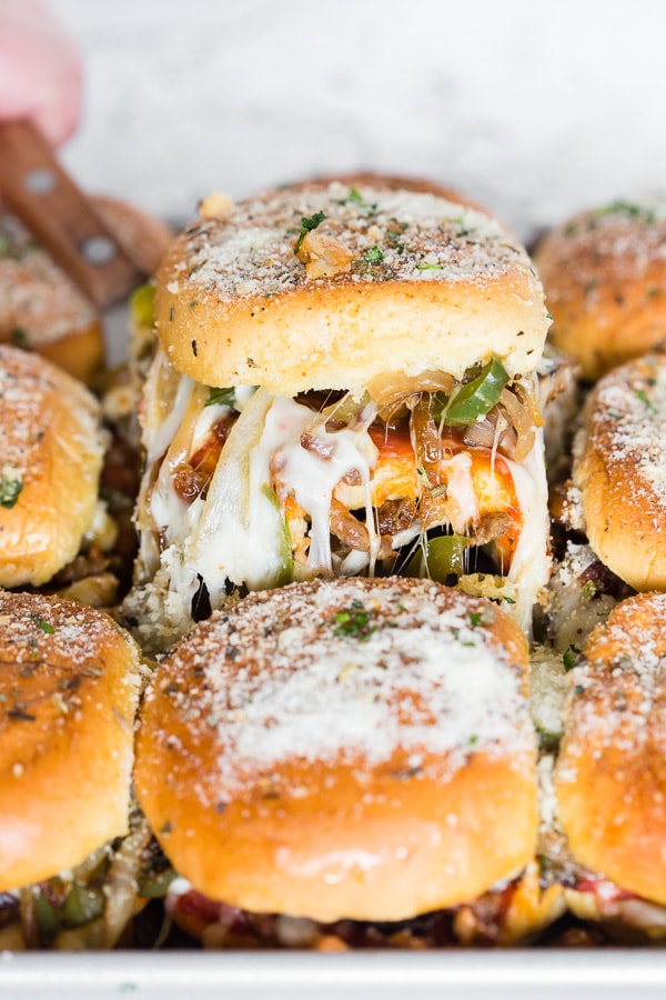 Baked Supreme Pizza Sliders being pulled out of the dish. 