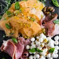 This cantaloupe Prosciutto Caprese salad is the perfect spring and summer salad. Sweet melon mixed with fresh mozzarella, pistachio nuts, Proscuitto, fresh basil and drizzle of honey and olive oil. You're going to love this simple summer salad!
