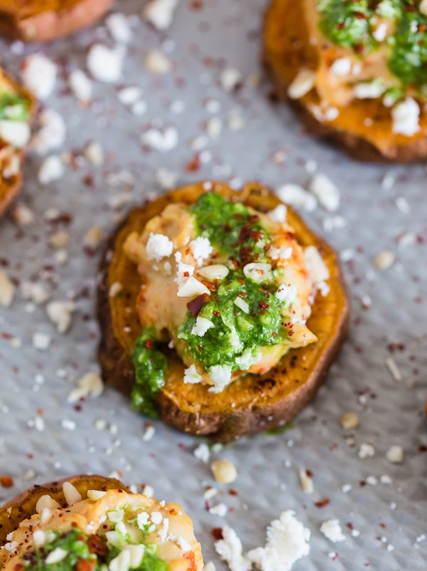 These pesto hummus sweet potato bites are the perfect bite size appetizer. Sumac roasted sweet potato rounds topped with spicy hummus, drizzled with spinach pesto and sprinkled with crumbled feta - how delicious is that! 