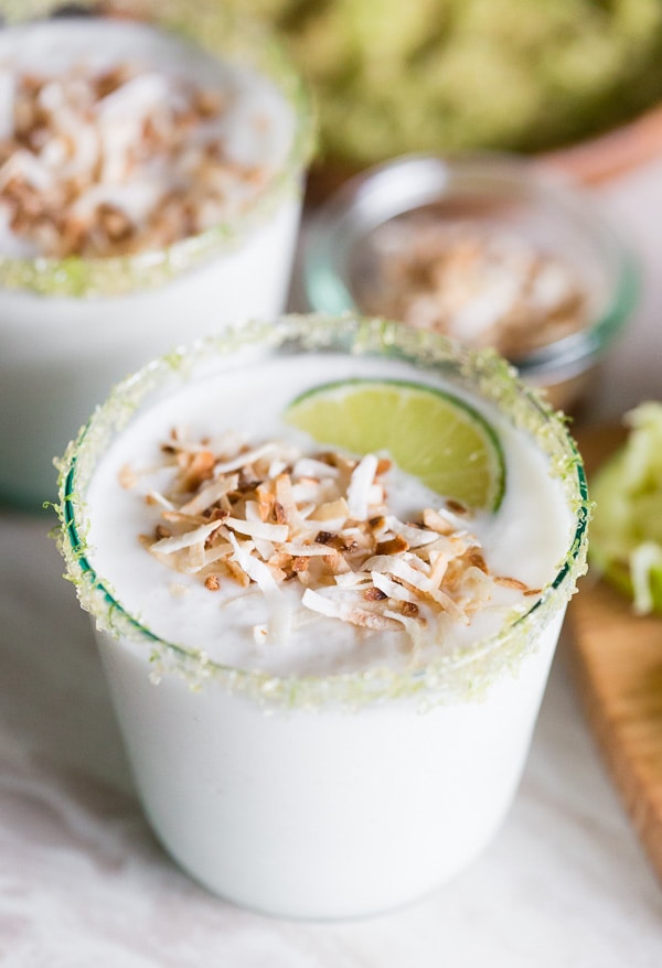 coconut lime frozen margarita in a glass with toasted coconut and lime.
