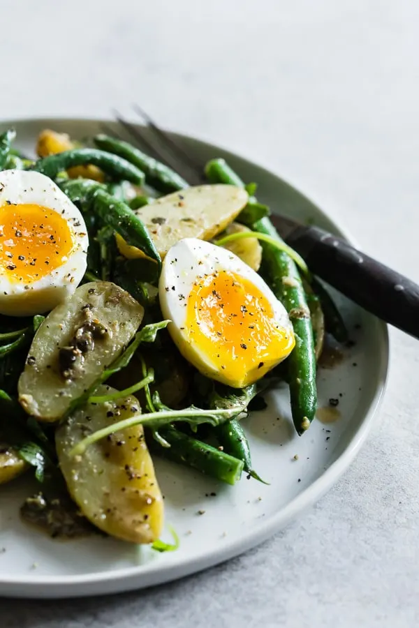 This tangy green bean potato salad is the perfect combination of buttery fingerling potatoes, crunchy blanched green beans, peppery arugula and soft boiled eggs all tossed in a creamy Dijon and caper vinaigrette. It's tangy, perfect for hot summer nights and makes an amazingly fast and easy meatless dinner! 
