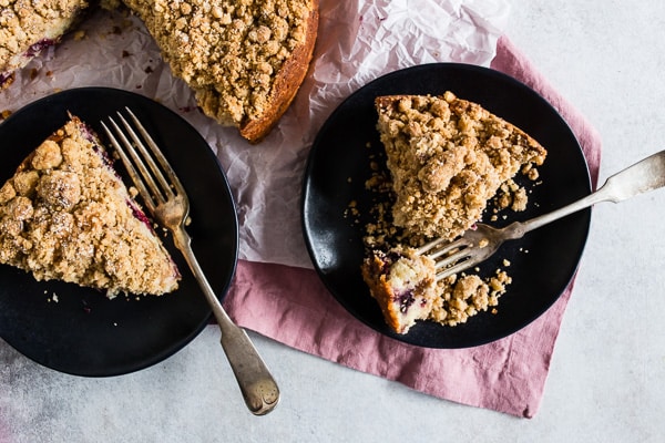 Two slices of berry coffee cake on a black plate.