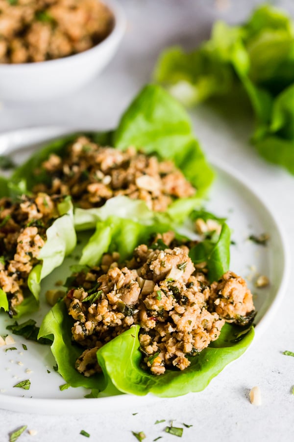 Thai Ground Chicken Lettuce Cups on a plate with herbs sprinkled on top. 