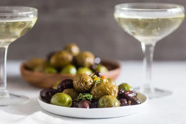 These garlic herb roasted olives are the perfect snack food! They are salty, packed full of garlic, thyme and orange flavor and are ready in just 15 minutes! They pair perfectly with prosecco and will be sure to impress all the olive lovers in your life. 