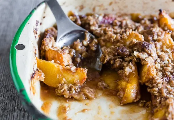 ginger peach crisp in a metal dish with spoon