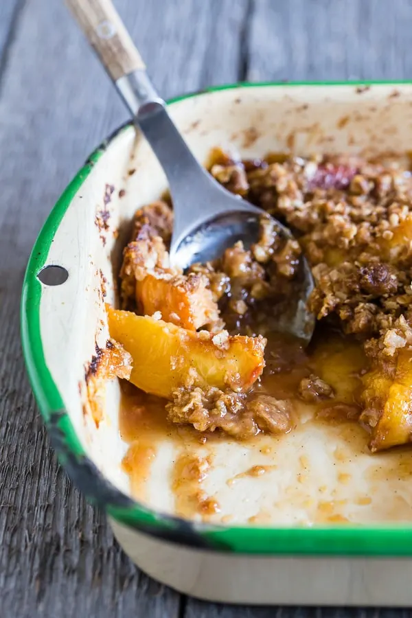 giner peach crisp in a metal pan with a little scooped out