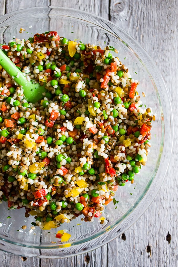 This lentil couscous goat cheese salad is PACKED full of flavor and the perfect meatless meal, light summer lunch or delicious side dish. Green lentils mixed with Israeli couscous, goat cheese, bell peppers, green peas, sun dried tomatoes, and parsley all drizzled with a homemade lemon, basil, and honey vinaigrette.