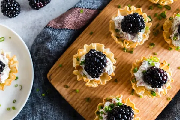 These goat cheese prosciutto blackberry phyllo bites are a delicious addition to any holiday party - tangy goat cheese mixed with cream cheese, chives, crispy prosciutto and topped with a fresh blackberry. This fun appetizer is the perfect little 2 bite treat! 