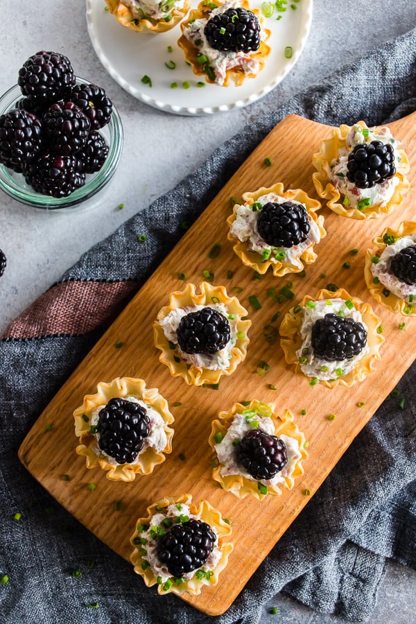 These goat cheese prosciutto blackberry phyllo bites are a delicious addition to any holiday party - tangy goat cheese mixed with cream cheese, chives, crispy prosciutto and topped with a fresh blackberry. This fun appetizer is the perfect little 2 bite treat! 