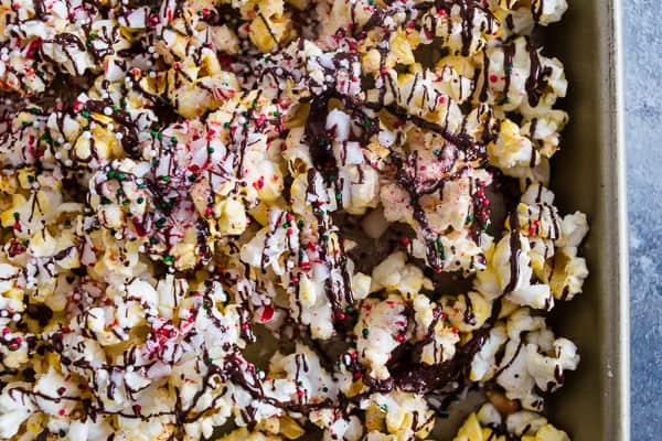 This peppermint bark popcorn is the EASIEST Christmas candy snack ever! Lightly buttered popcorn topped with white chocolate, dark chocolate, crushed candy canes, and sprinkles. You'll love this flavor packed snack!