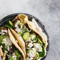 These Greek chicken meatball gyros are packed full of fresh herbs and feta cheese and topped with creamy tzatziki sauce and crunchy vegetables. They are a fun twist to traditional gyros and chicken souvlaki. 