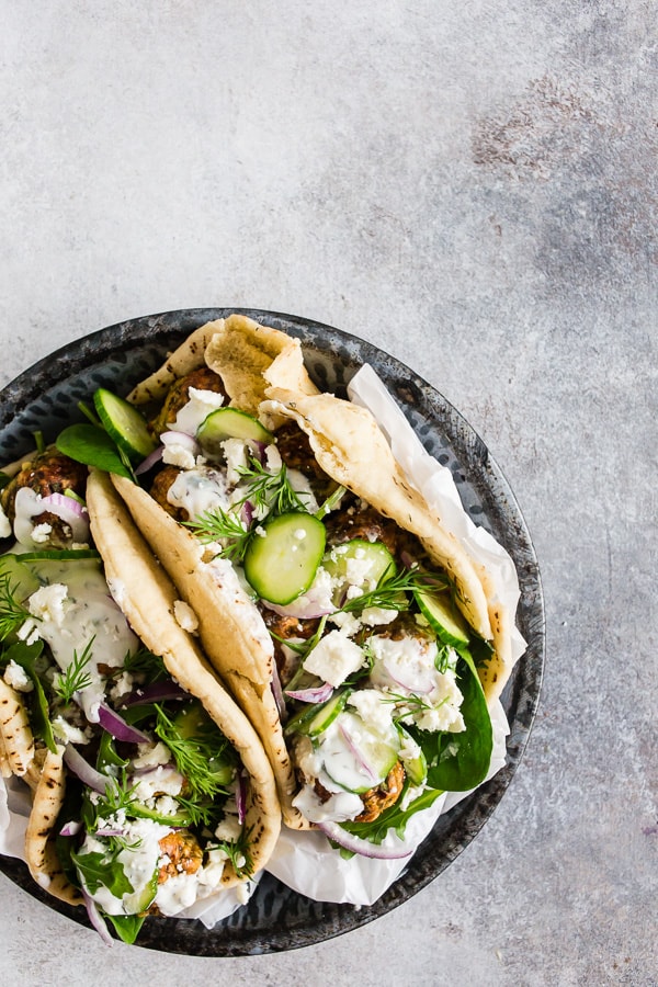 These Greek chicken meatball gyros are packed full of fresh herbs and feta cheese and topped with creamy tzatziki sauce and crunchy vegetables. They are a fun twist to traditional gyros and chicken souvlaki. 