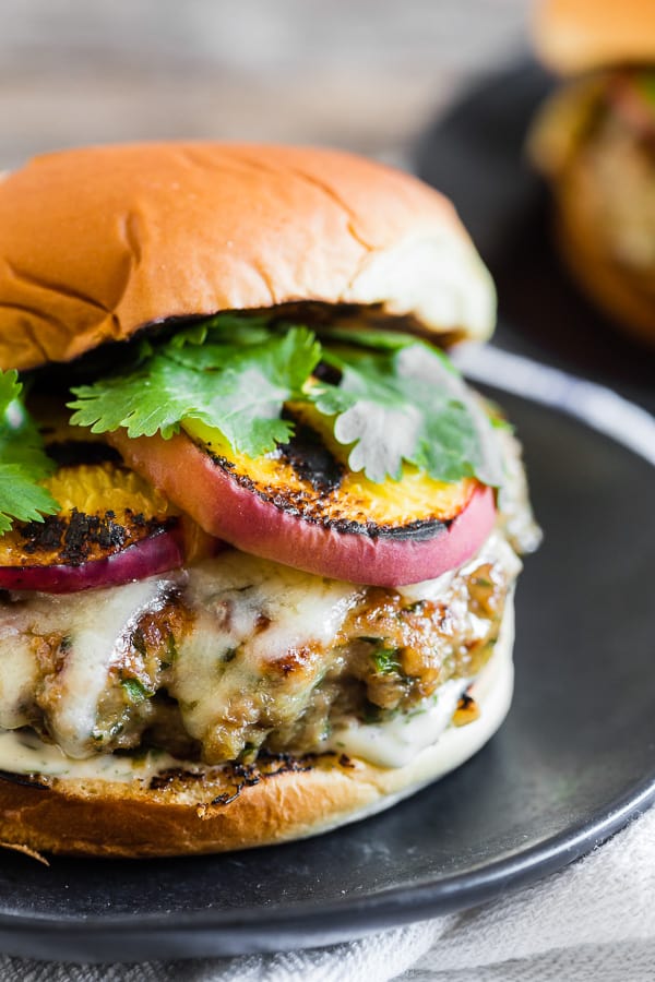 This cheesy grilled peach jalapeno turkey burger is the perfect combination of sweet and spicy. Fresh summer peaches grilled to bring out their sweetness and paired with a herb, cheese and jalapeno packed turkey burger and topped with sharp cheddar cheese and a sprinkling of cilantro. If you’re a fan of sweet and heat this burger is for you!