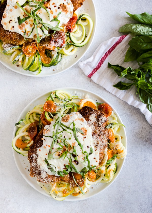 This summer chicken Parmesan with zoodles is made with fresh sauteed garlicky tomatoes, crispy chicken covered in fresh mozzarella cheese and served with fresh spiralized zucchini noodles. It's a fresh spin to the traditional recipe and the perfect use for all those summertime vegetables.