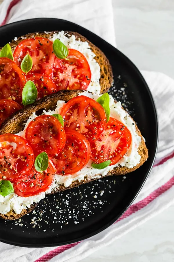 This ricotta tomato toast is my favorite way to start the day. Crunchy toasted whole wheat sourdough spread with creamy ricotta cheese and topped with sun-ripened tomatoes, kosher salt, and black pepper. For an extra boost of flavor add some fresh basil leaves. 