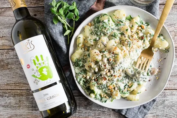 creamy gorgonzola gnocchi on a plate with a bottle of wine. 