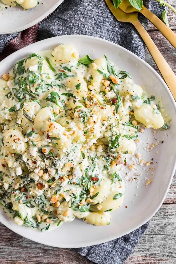 creamy gorgonzola gnocchi on a plate topped with sprinkled pine nuts. 