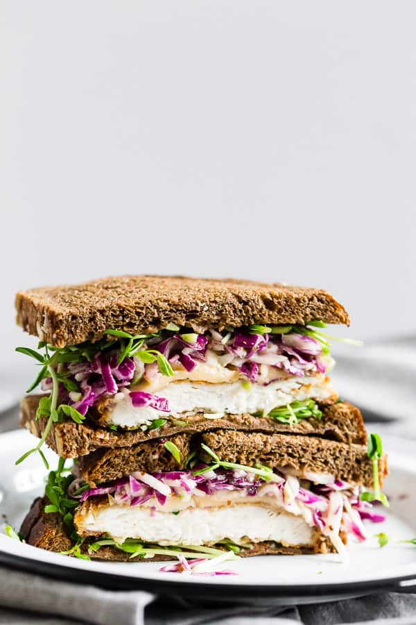 This crispy chicken sandwich with cabbage apple slaw takes the flavors of fall and puts them into a sandwich. It’s a perfectly cooked crispy chicken cutlet topped with smoked Gouda cheese, pea shoots, and a homemade tangy red cabbage apple slaw. You’ll love this killer sandwich.