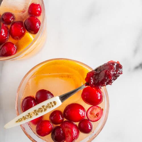 Crimson Gin Sparkler 4 Ingredients laid out for a Cranberry Gin Fizz, showing gin, orange, and cranberry sauce.