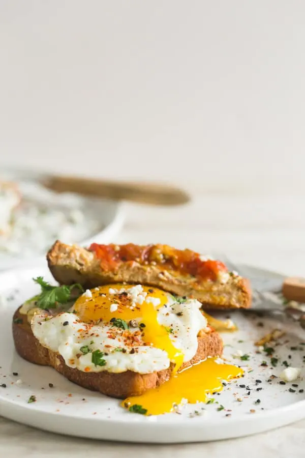 Shakshuka Hummus Toast topped with a runny egg. 