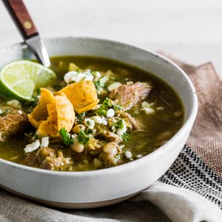 This Instant Pot pork chili verde is packed full of tomatillos, cilantro, diced green chiles, fork-tender pork shoulder, and white beans. It's perfect for cold snowy days and tastes great when topped with Cotija cheese, cilantro, and crispy corn chips. 