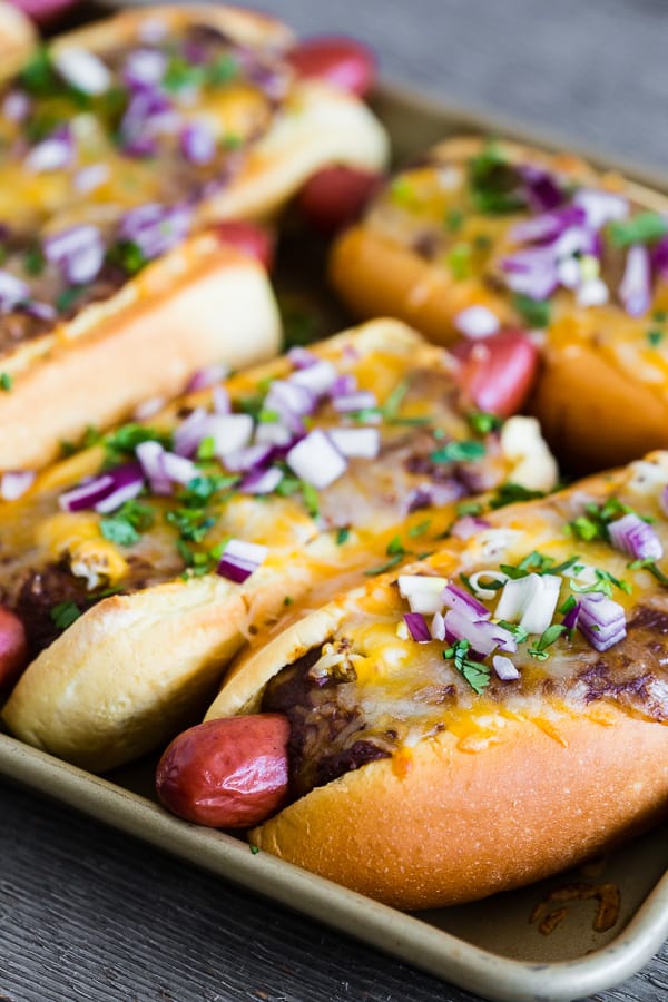 Oven Baked Chili Cheese Dogs served with fresh cilantro and red onion. 