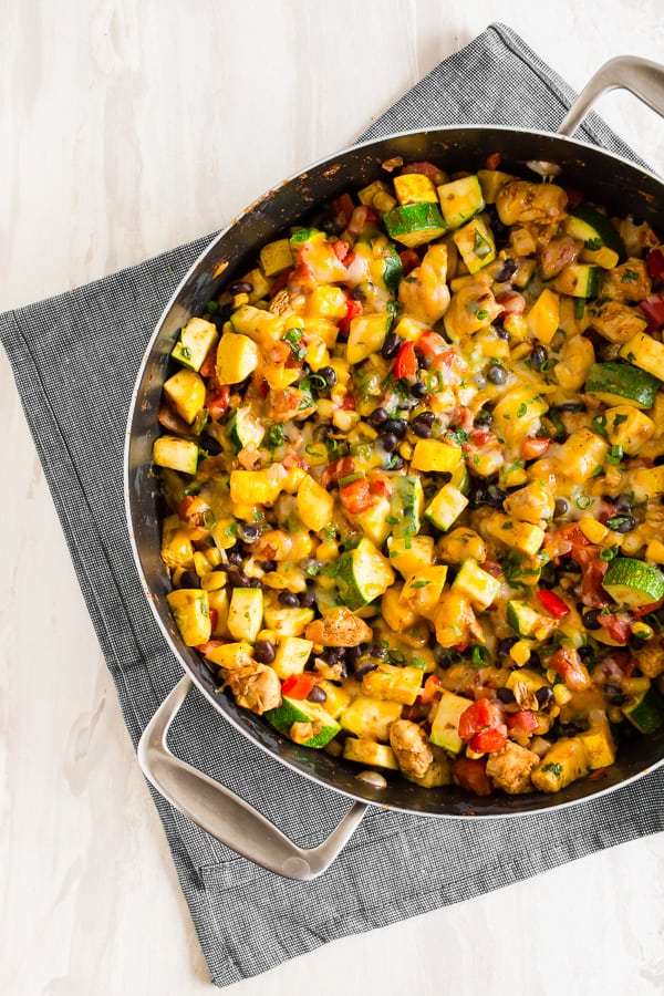 tex mex chicken and vegetable skillet in a large skillet topped with melted cheese.