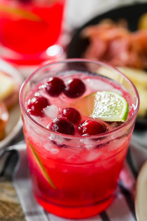 cranberry lemonade ginger beer cocktail in a glass garnished with lime and cranberries