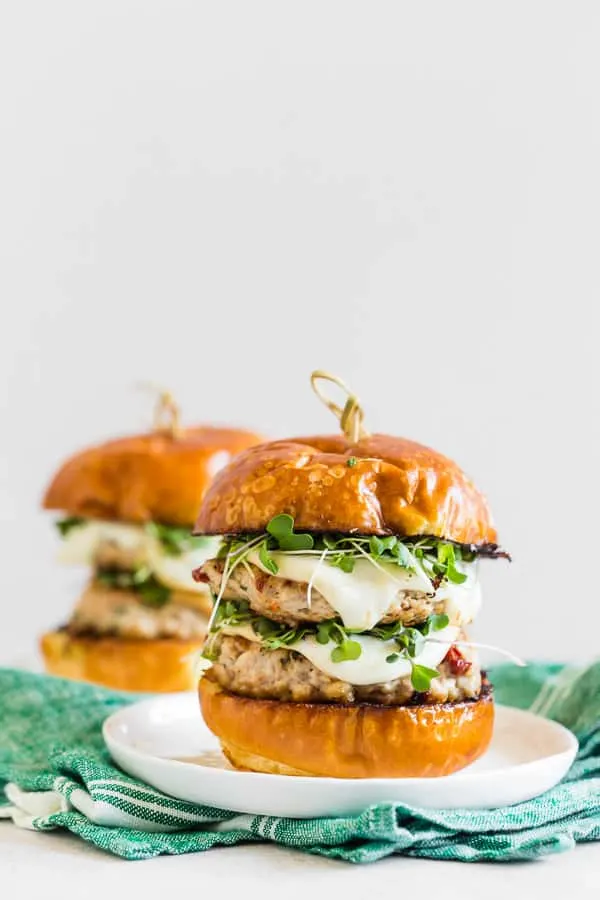 two sun dried tomato chicken burgers on a plate