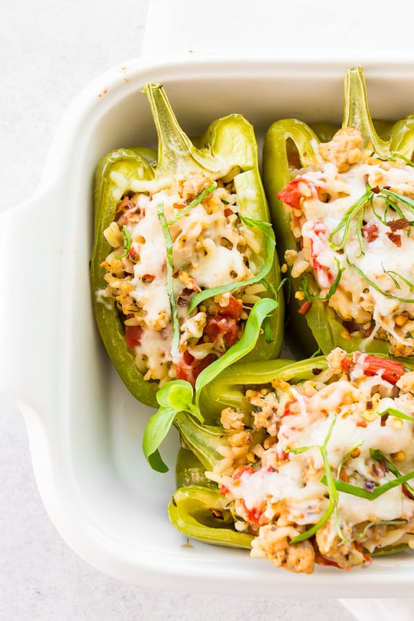ground chicken stuffed bell peppers in a small white casserole pan
