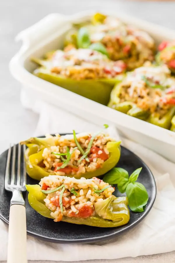 ground chicken stuffed bell peppers cut in half and sitting on a small plate with a fork