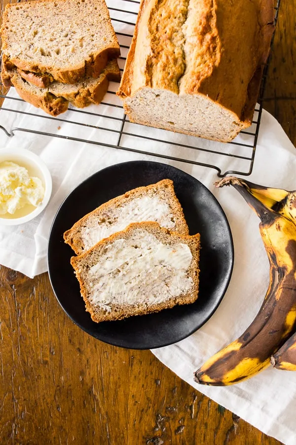 sourdough discard banana bread sliced on a plate with butter