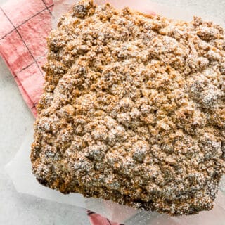 sourdough discard cinnamon crumb cake on parchment paper with a pink napkin underneath