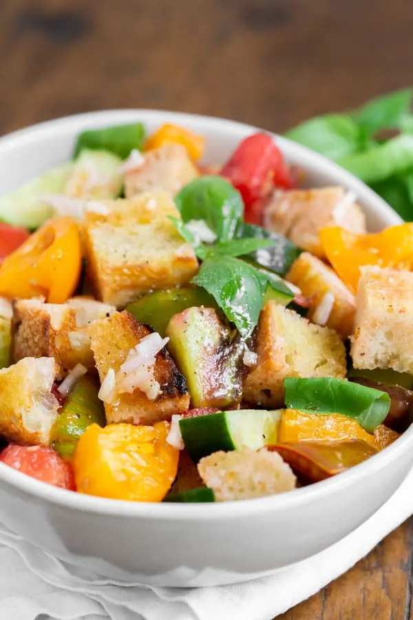 grilled sourdough panzanella salad in a white bowl with fresh basil