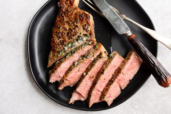 sliced cast iron seared strip steak steak on a black plate