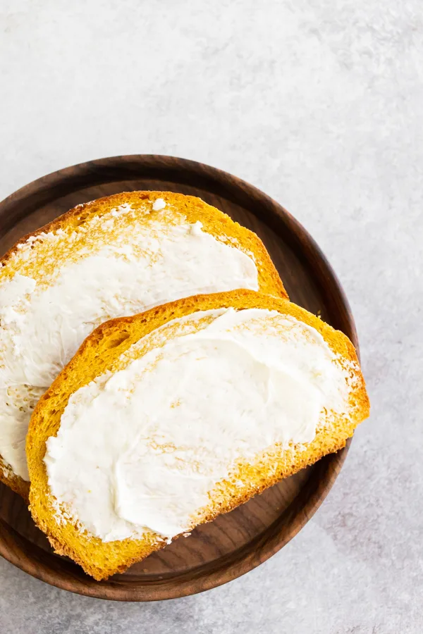 Pumpkin Yeast Bread sliced on a plate with butter