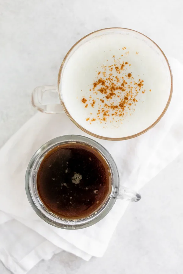 homemade cinnamon dolce syrup in a jar with a cup of hot coffee