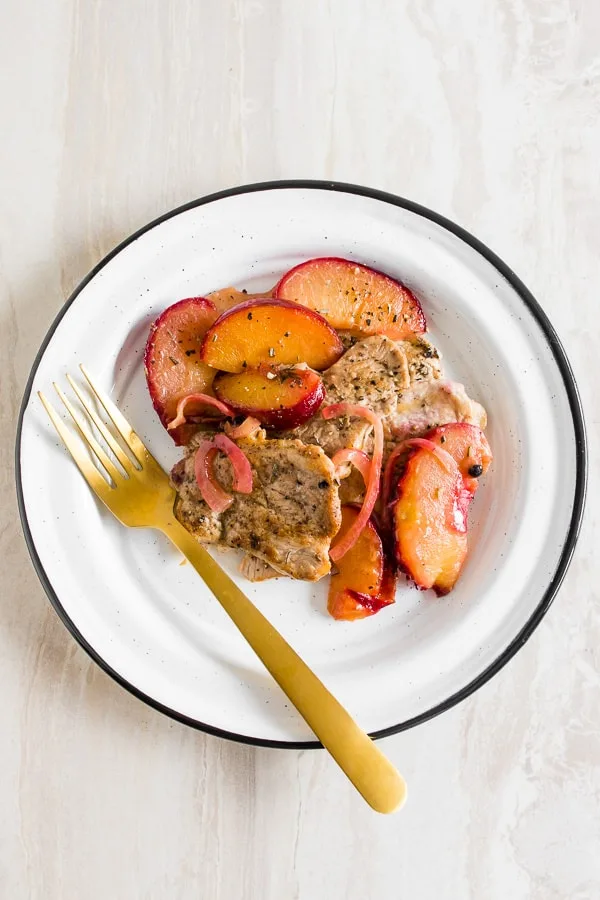 skillet pork tendrloin with plums shot from overhead on a plate with a fork.