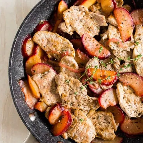pork with plums in a skillet shot from overhead