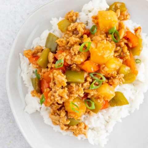 sweet and sour ground chicken on a white plate with white rice