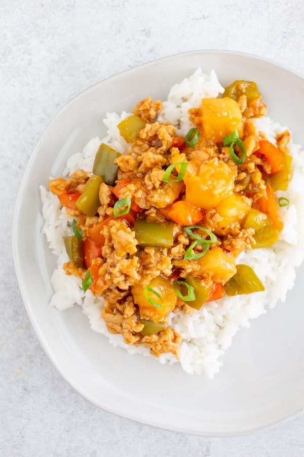 sweet and sour ground chicken on a white plate with white rice