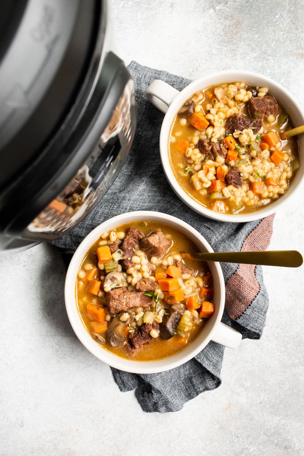 Instant pot beef barley soup in bowls sitting next to an Instant Pot