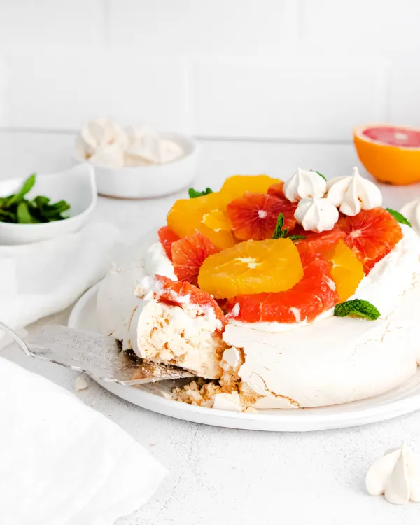 a slice being taken out of a winter citrus pavlova