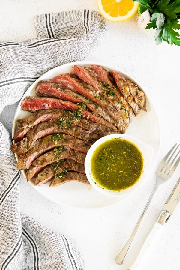 grilled chimichurri flank steak on a serving dish. 