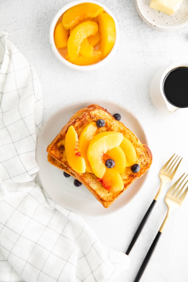 Peach Topped French Toast on a small plate with extra peaches on the side.