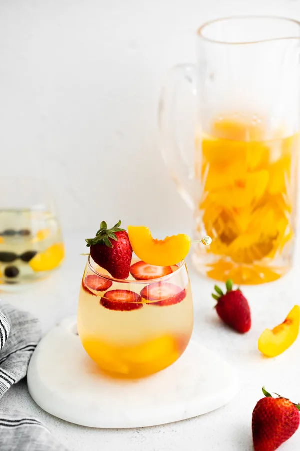 strawberries and peaches in a glass with white wine peach sangria.